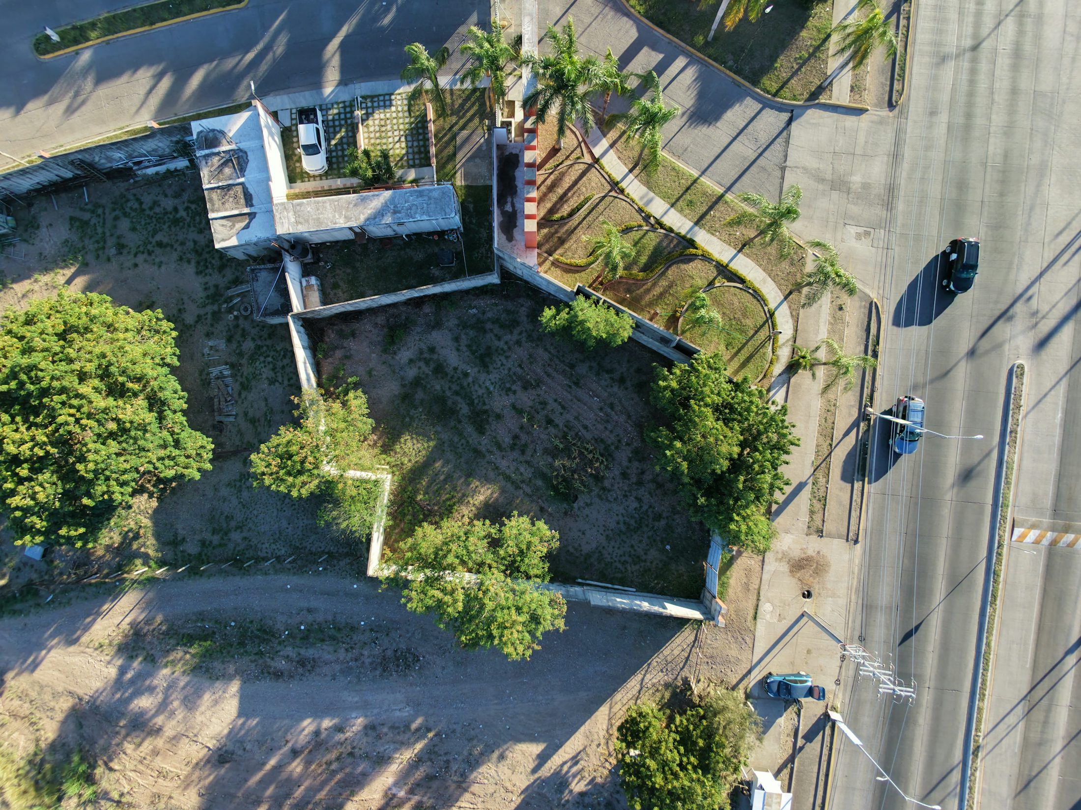 Vue aerienne d'une parcelle vacante borde de voiries et de plantations.