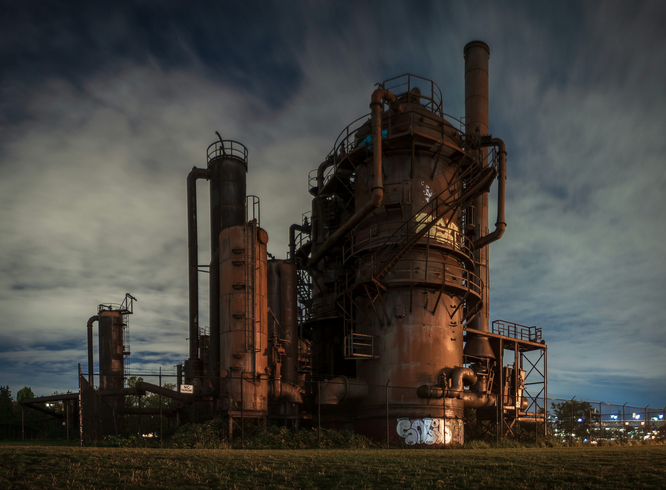 Ancienne raffinerie industrielle au crepuscule, avec une presence forte et brute.