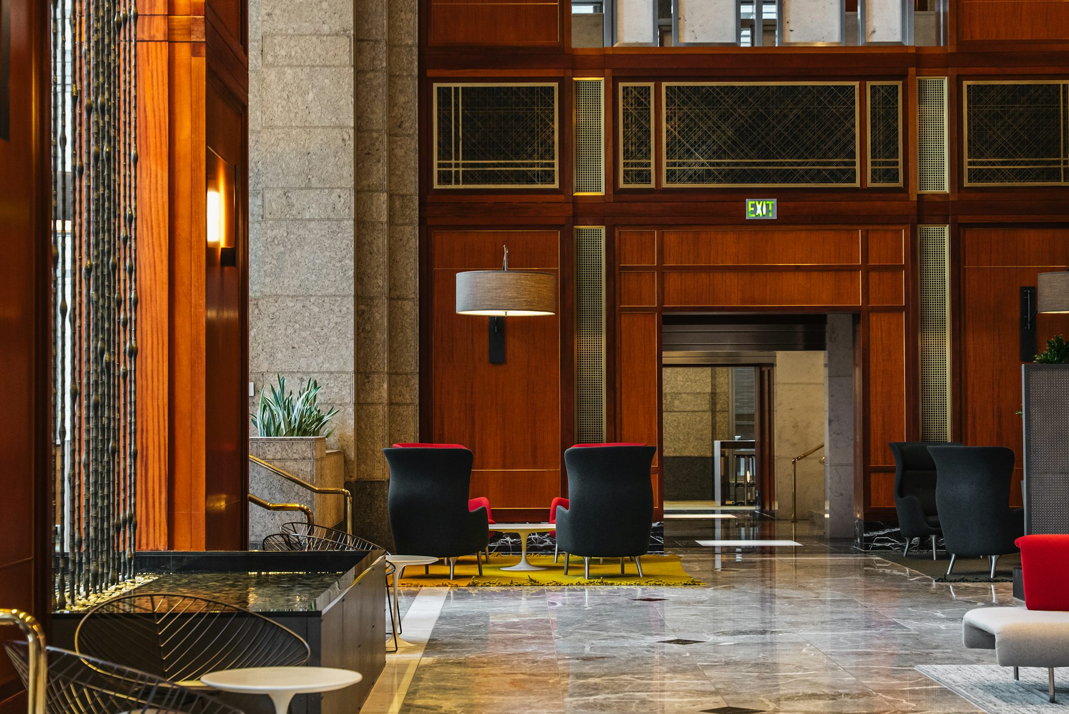 Lobby hotelier elegant avec boiseries, fauteuils et finitions haut de gamme.